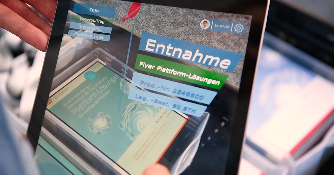 Auf diesem Bild wird Augmented Reality auf dem Tablet angewandt, um eine Handling Unit zu identifizieren: Die Darstellung der weiterführenden Informationen wird ebenfalls anhand der überlagerten Räumlichkeit dargestellt.