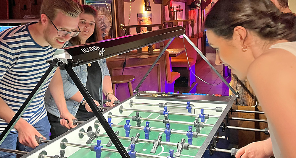 Auf diesem Foto sind vier Würzburger Kolleginnen und Kollegen am Kickertisch zu sehen.